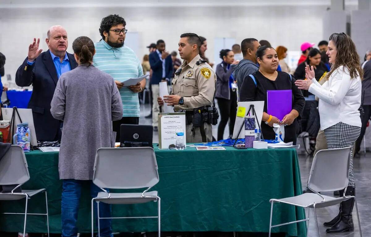 Los solicitantes de empleo hablan con el personal del Departamento de Policía Metropolitana du ...