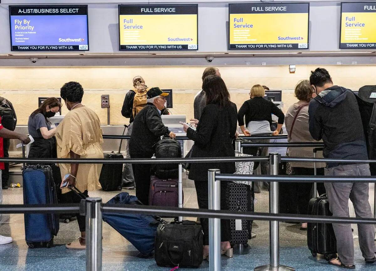 Los pasajeros hacen fila para registrarse en el mostrador de registro de Southwest en la Termin ...