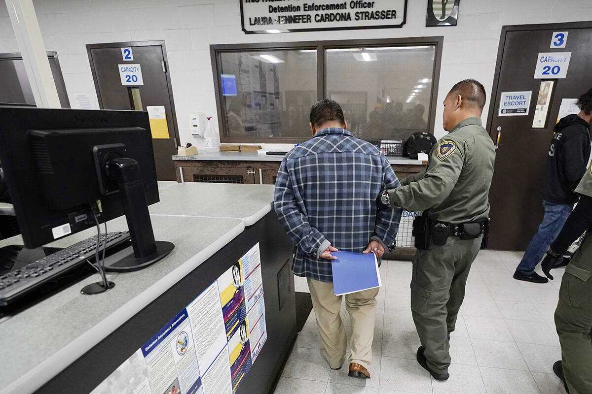 Un oficial escolta a un hombre detenido en un centro de procesamiento de inmigración y aduanas ...