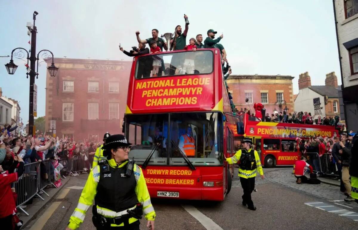 Miembros del equipo de fútbol Wrexham FC viajan en un autobús descapotable mientras celebran ...