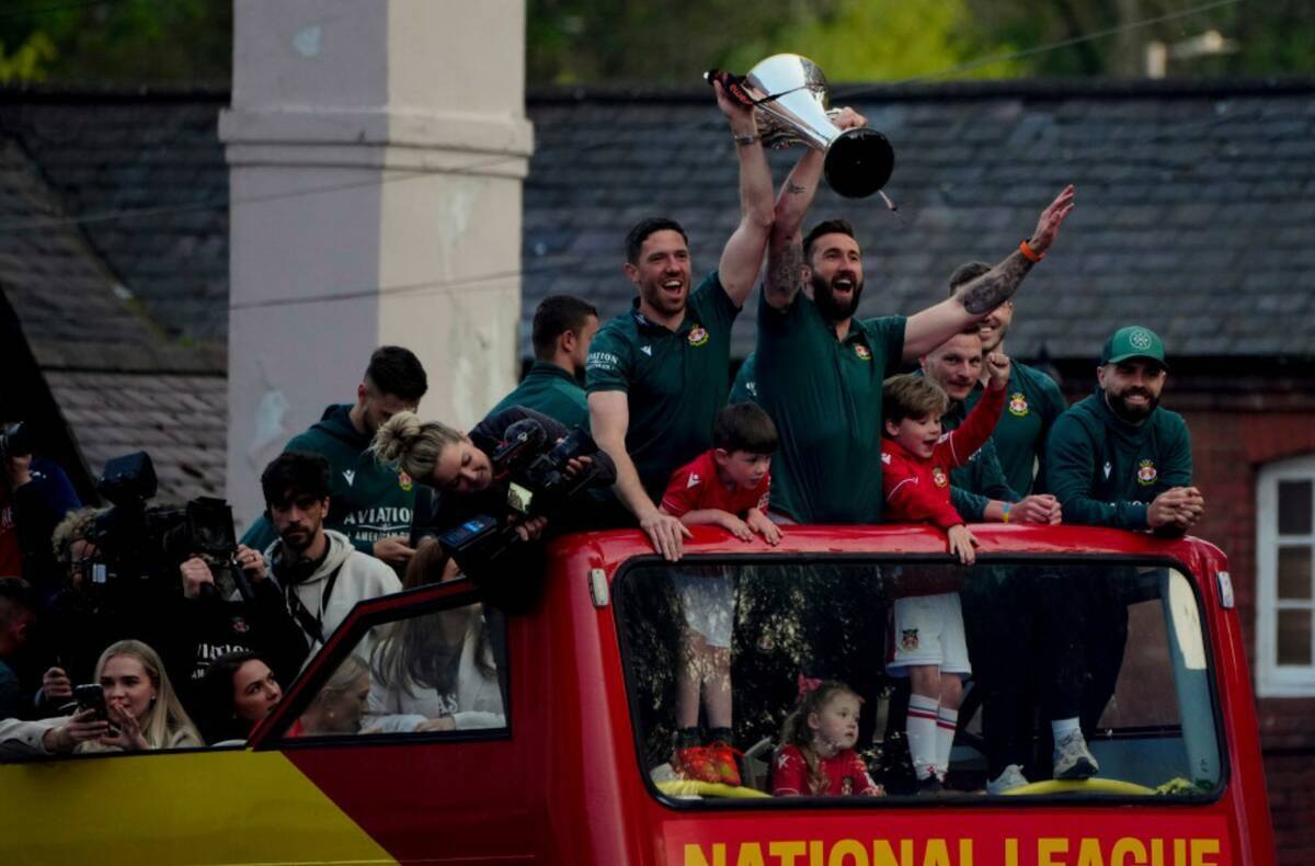 Miembros del equipo de fútbol Wrexham FC viajan en un autobús descapotable mientras celebran ...