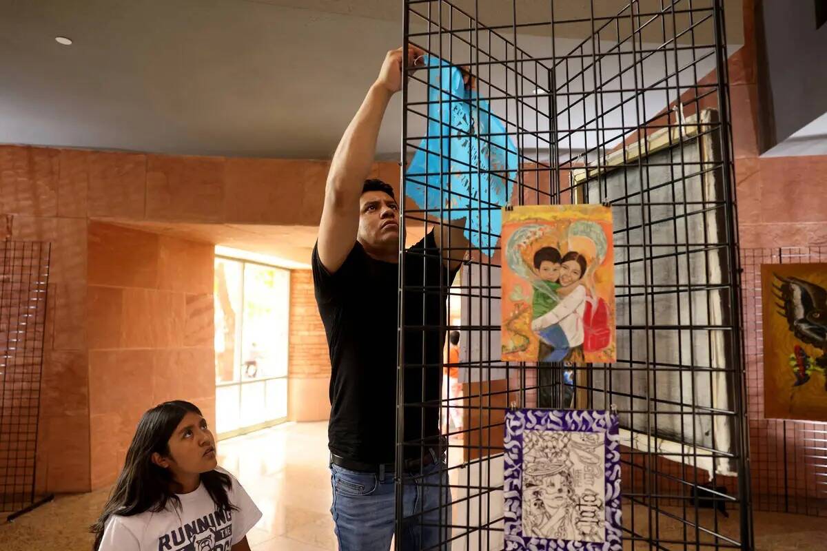 Meliton Monterrosas ayuda a montar una exposición del artista mexicano visitante Olegario Hern ...