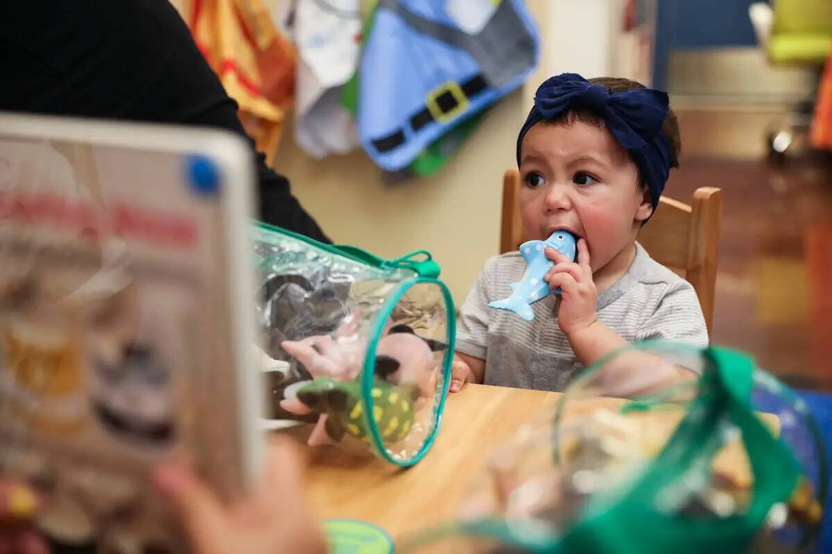 Leah Magallanes, de un año, muerde un juguete en el área de niños recién donados en un even ...