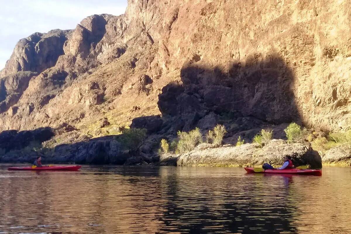 Los kayakistas reman entre las sombras de la mañana en la ruta Black Canyon National Water Tra ...