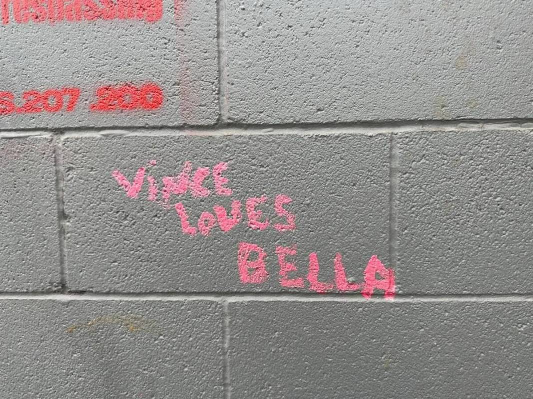 Las palabras "VINCE LOVES BELLA" son visibles en una pared cerca de un campamento improvisado d ...