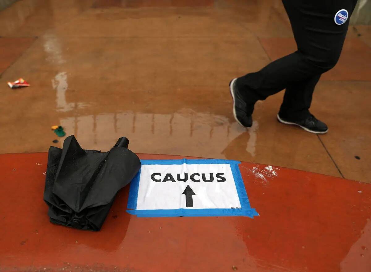 La lluvia cae mientras las personas llegan a registrarse para el caucus en East Las Vegas Commu ...