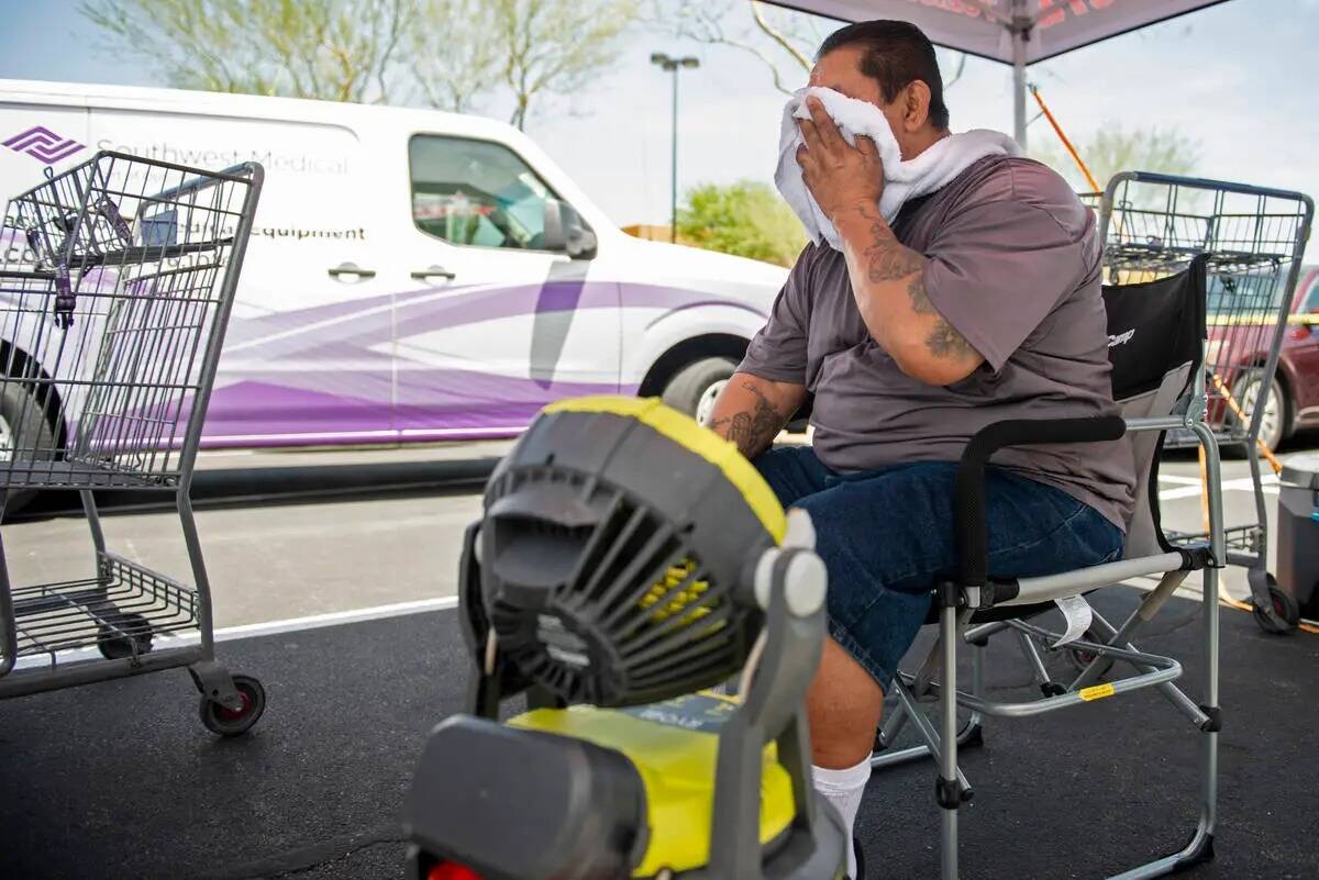 Gus Álvarez se refresca con un ventilador y una cubeta de agua fría mientras trabaja en una c ...