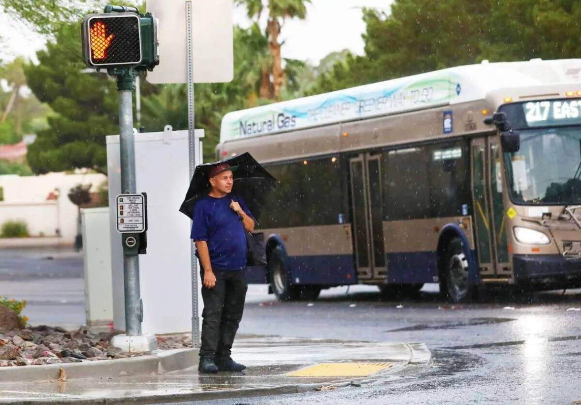 Un hombre espera para cruzar Pecos Road durante una tormenta de lluvia temprano en la mañana e ...