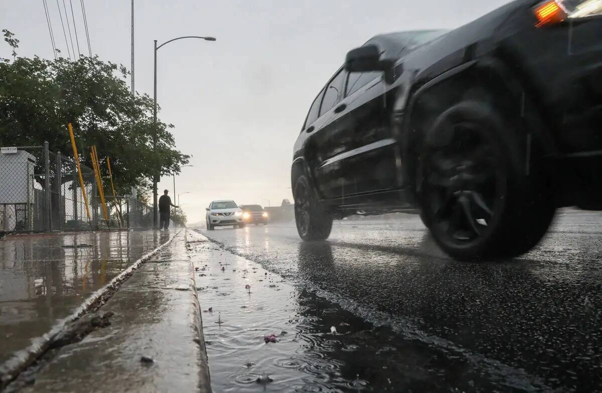 Autos circulan a lo largo de Warms Springs durante una tormenta de lluvia temprano en la mañan ...