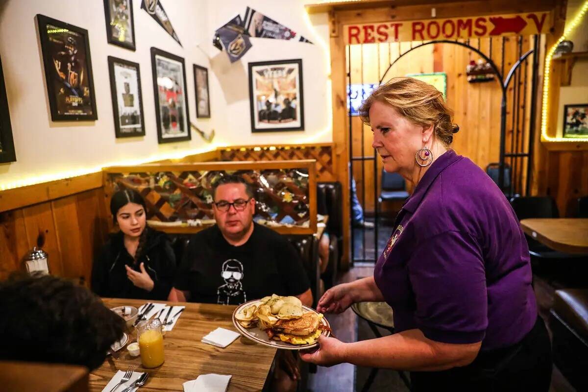 La mesera Katy Lehmann lleva comida a una familia que cena en The Omelet House en su céntrico ...