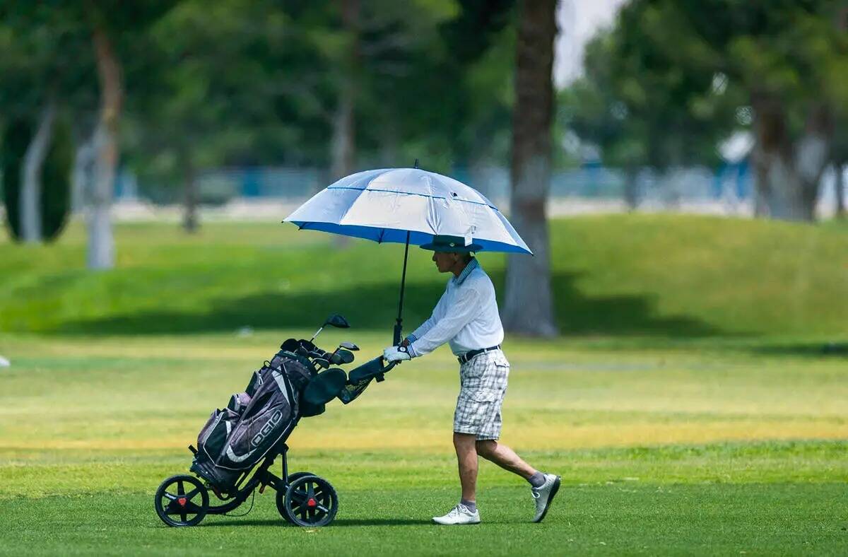 Un jugador de golf se mantiene fresco bajo un paraguas en el campo del Club de Golf de Las Vega ...