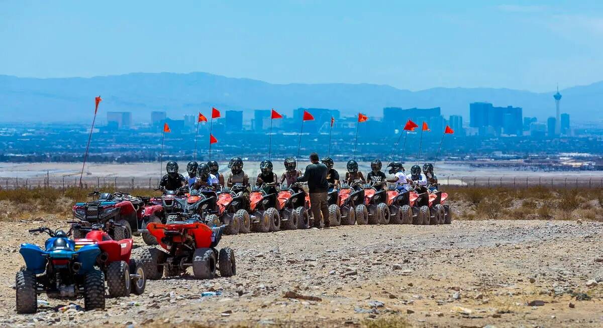 Pilotos de ATV reciben instrucciones antes de un paseo dentro de las dunas de Nellis mientras e ...