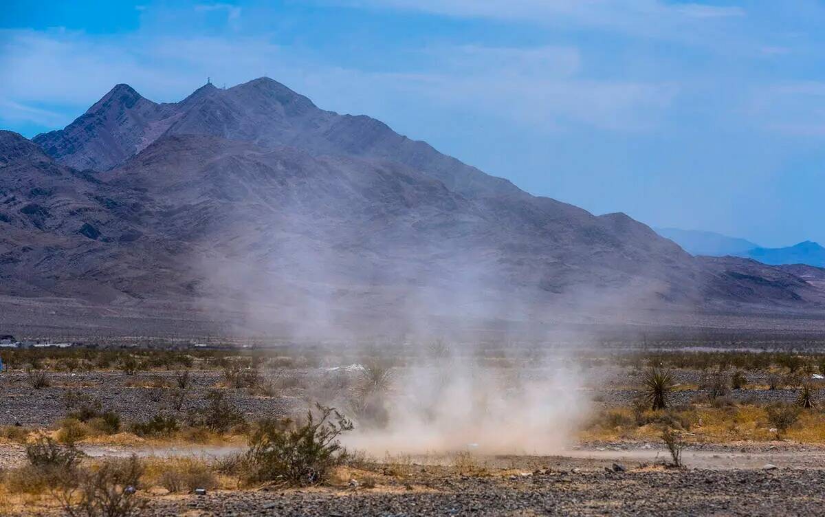 Un remolino de polvo gira a través del desierto dentro de las dunas de Nellis mientras el calo ...