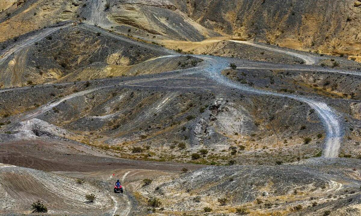 Un piloto de ATV navega por un camino dentro de las dunas de Nellis mientras el clima caliente ...