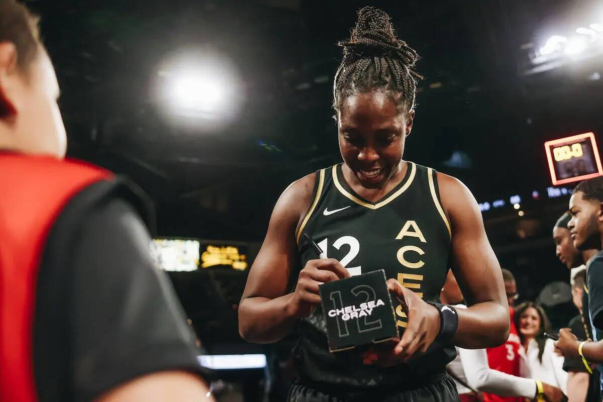 La escolta de Las Vegas Aces Chelsea Gray firma un muñeco suyo para un fan tras vencer a las I ...