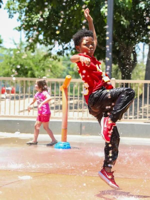 Trent Turner, de siete años, salta a través de los juegos de agua en Bob Baskin Park para ref ...