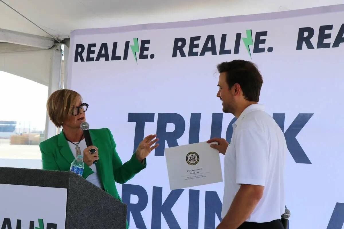 La representante federal Susie Lee entrega al director ejecutivo de Realize, Cody Horchak, un c ...