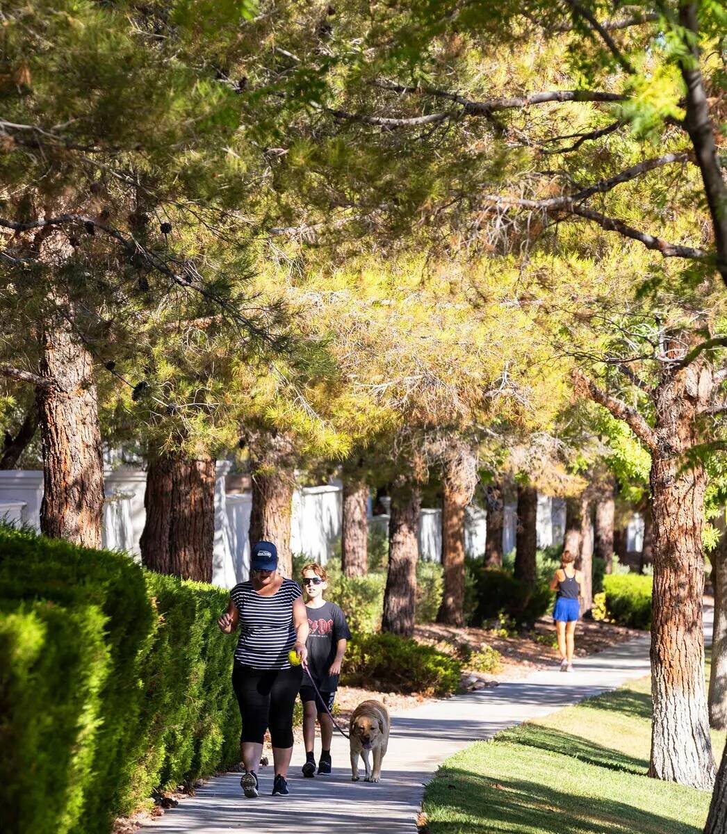 Peatones caminan por una acera cubierta de árboles a lo largo de Green Valley Parkway el jueve ...