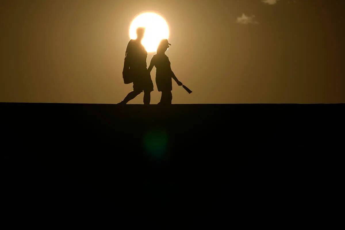 ARCHIVO - Un grupo de personas camina por un sendero mientras se pone el sol, el domingo 16 de ...