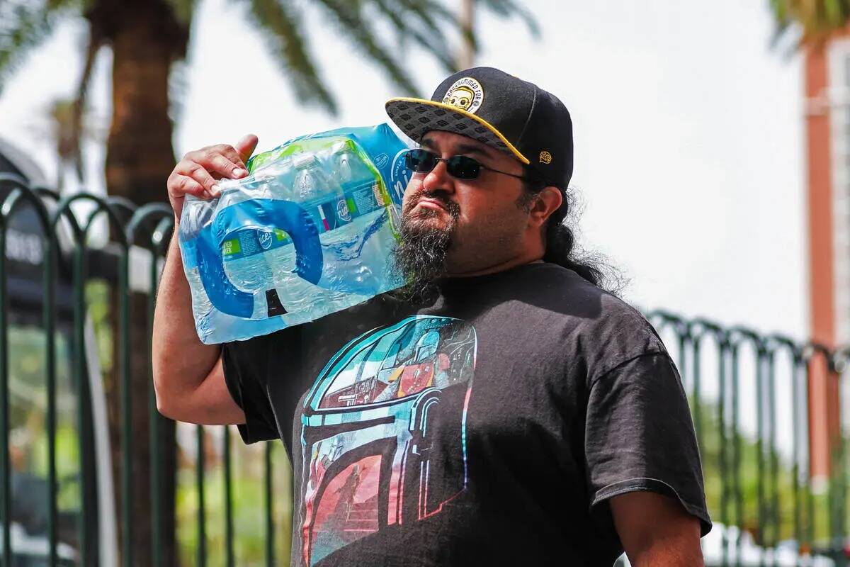 Un hombre lleva un recipiente lleno de agua a lo largo del Strip el lunes 31 de julio de 2023, ...