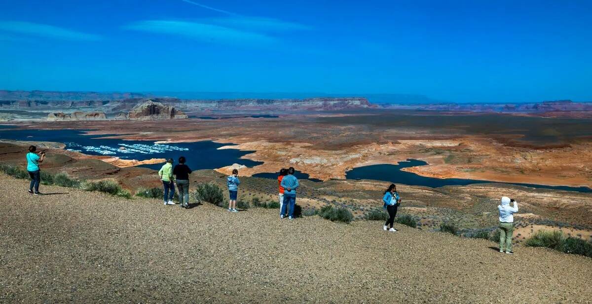 Visitantes contemplan desde lo alto el menguante Lago Powell, alimentado por el río Colorado, ...