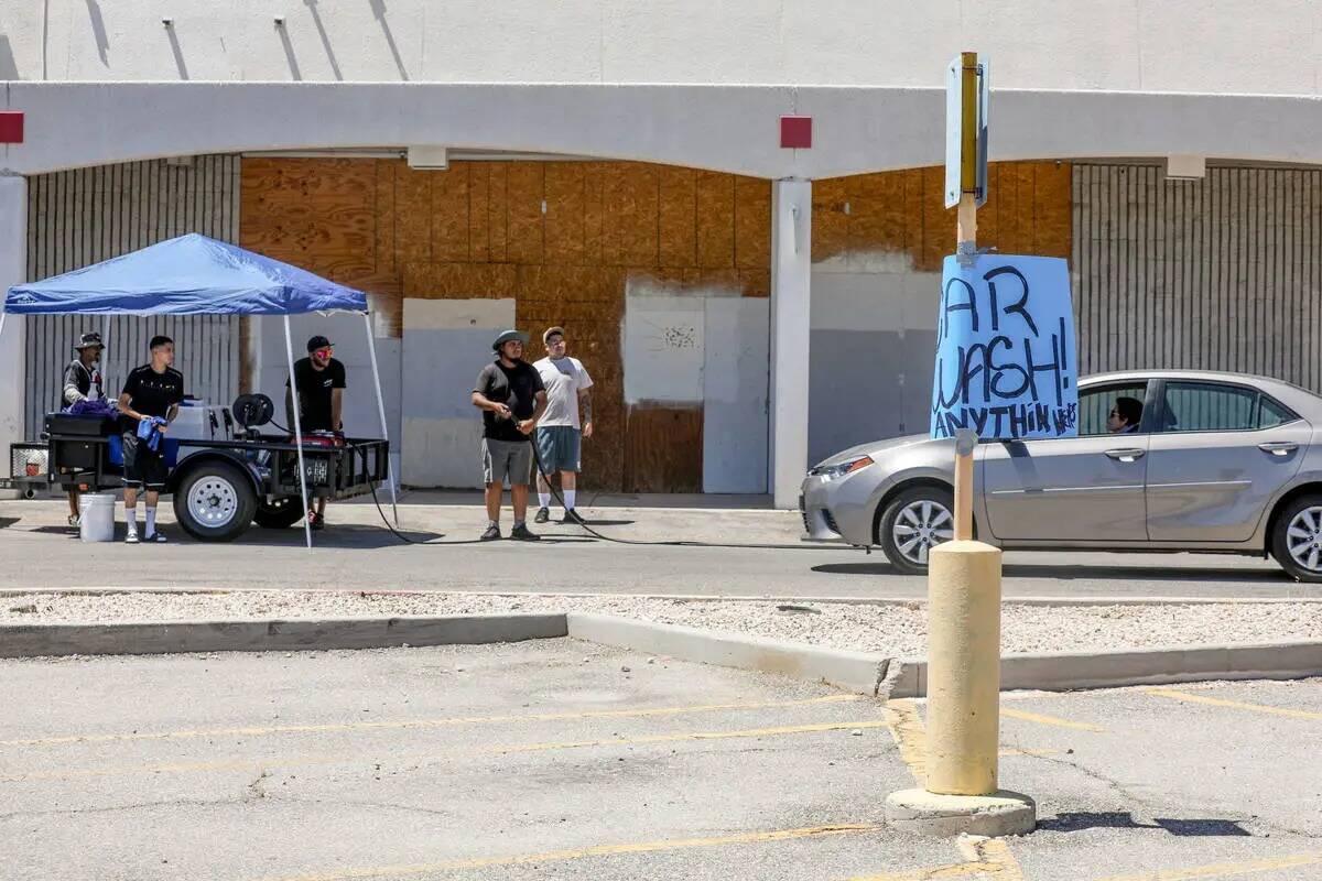 Miembros de la comunidad esperan a que un coche se detenga en un lavado de autos para recaudar ...