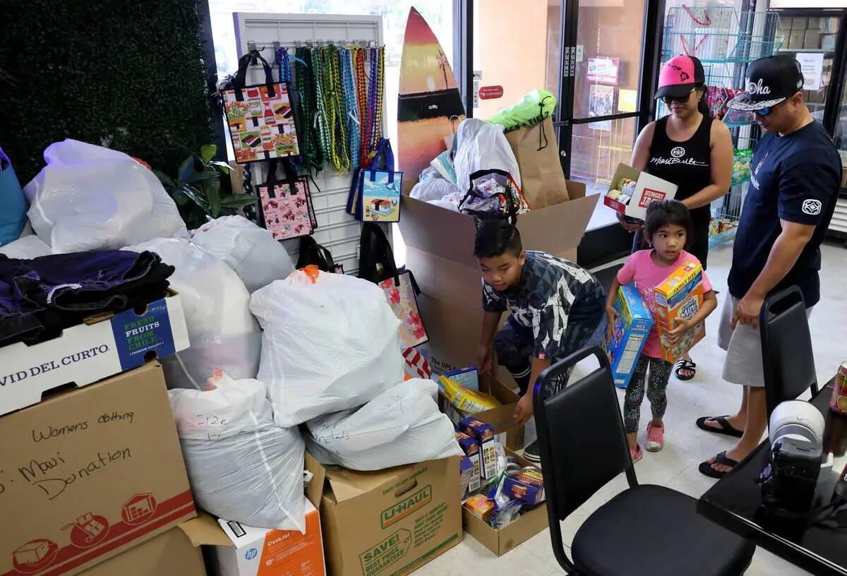 Jeden y Jeff Medina, originarios de Maui, entregan donaciones con sus hijos Jedson, de 9 años, ...