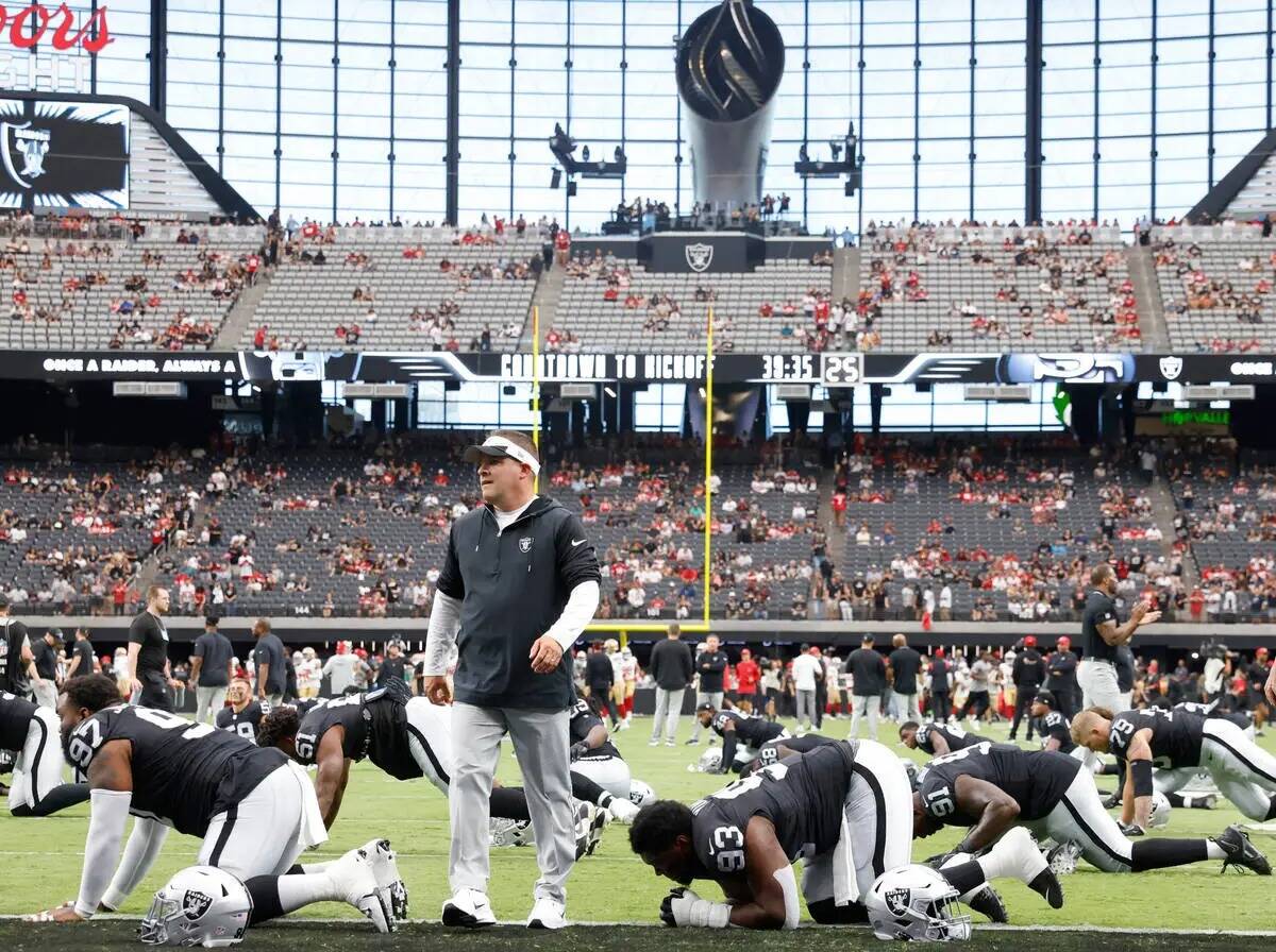 El entrenador de los Raiders, Josh McDaniels, observa a sus jugadores mientras estiran antes de ...