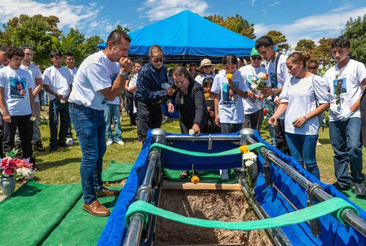 Rudolfo Naranjo, a la izquierda, llora mientras los miembros de la familia arrojan flores sobre ...