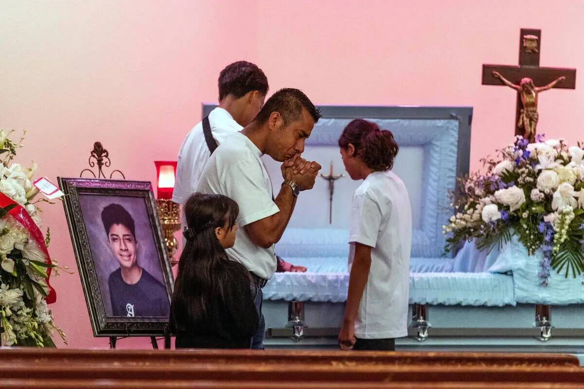 Rudolfo Naranjo reza junto a los miembros de su familia junto al ataúd de su hijo Ángel antes ...