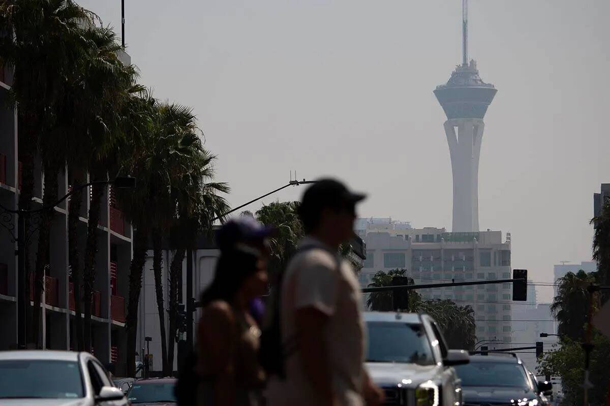 Peatones caminan por Fremont Street Experience mientras el cielo lleno de humo nubla el STRAT e ...