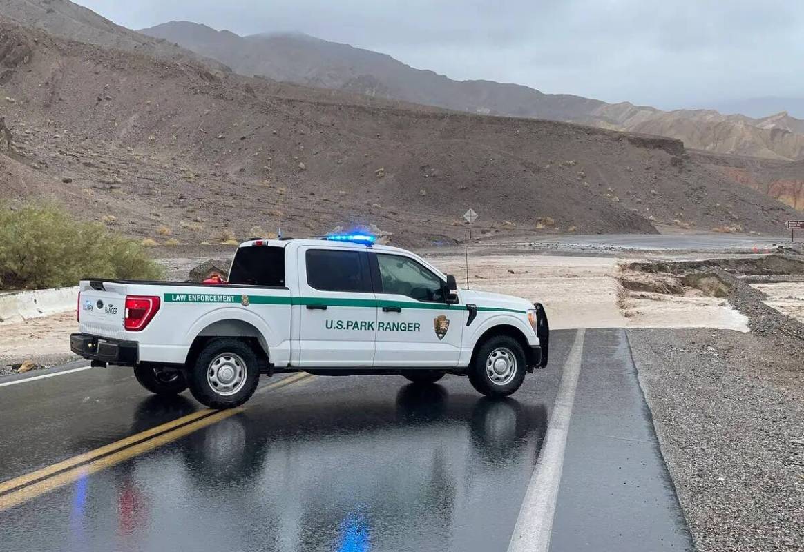 El agua cruza la carretera California 190 cerca de Zabriskie Point a las 10 de la mañana del d ...