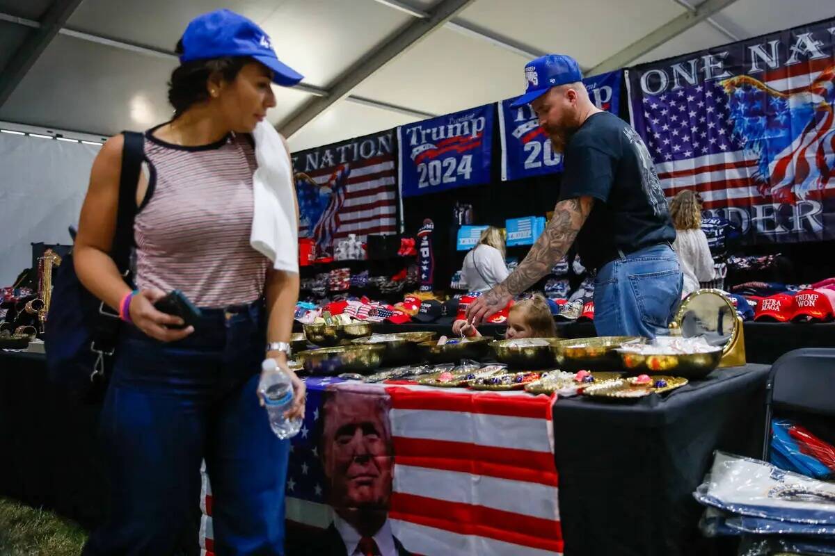 La gente echa un vistazo a la mercancía temática de Trump en el ReAwaken America Tour el vier ...