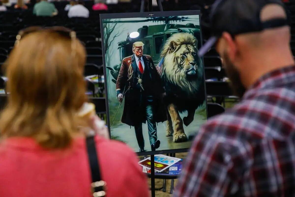 Una pareja admira una imagen artística de Donald Trump en ReAwaken America Tour el viernes 25 ...