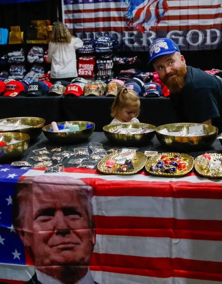 Sam Stafford y su hija Penelope Stafford, de tres años, exploran la mesa de mercancía de Trum ...