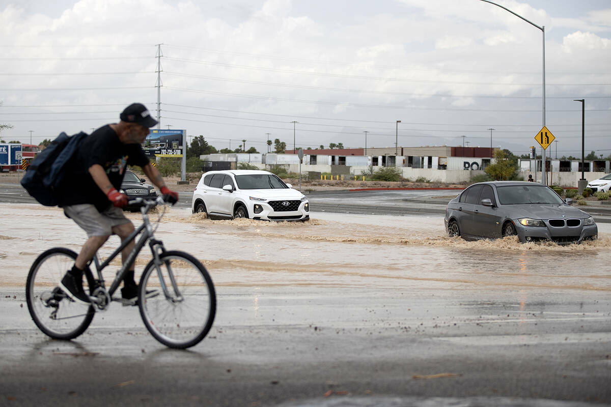 El tráfico transita por las aguas de inundación en West Sunset Road y South Decatur Boulevard ...