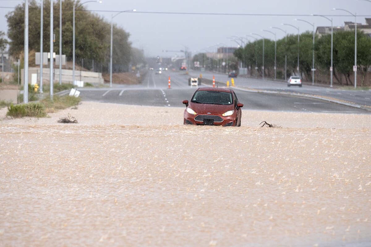 Un vehículo está varado en las aguas de una inundación repentina cerca de la intersección d ...