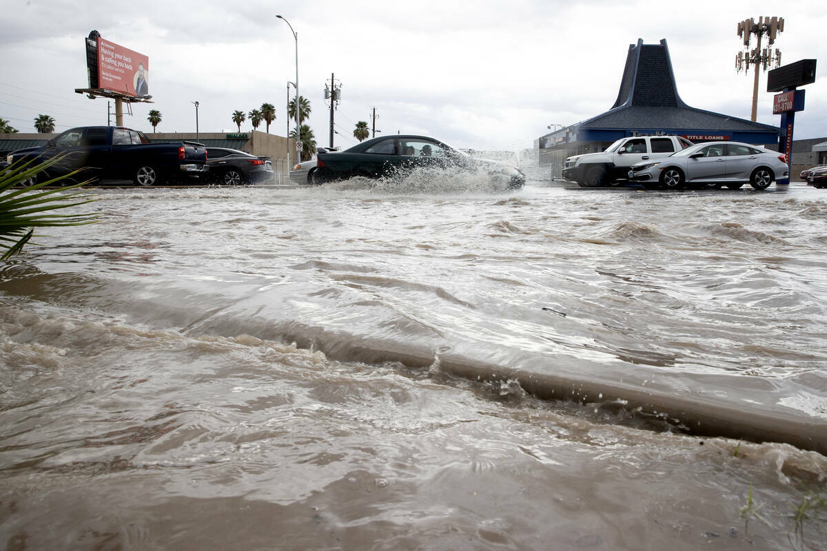 Inundaciones repentinas se derraman sobre la acera y en un estacionamiento, mientras el tráfic ...