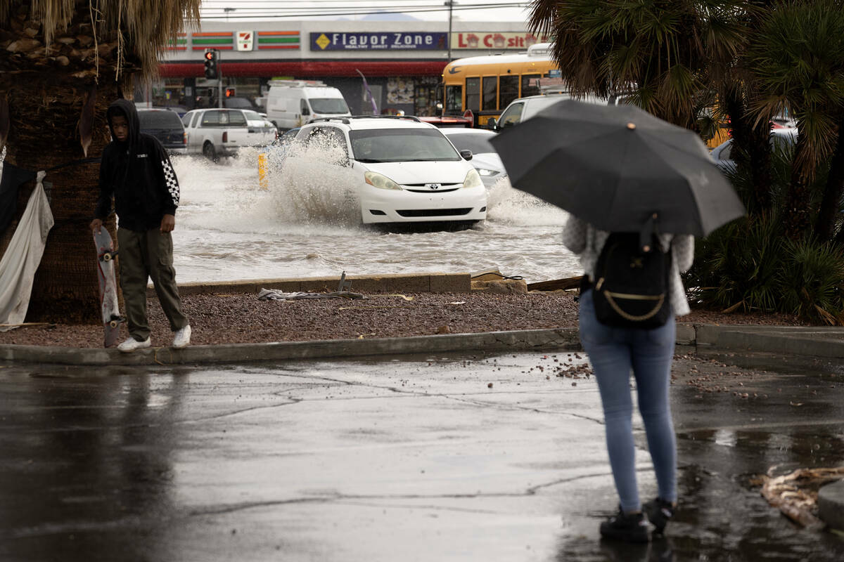 Peatones se detienen a observar las inundaciones repentinas en la intersección East Sahara Ave ...