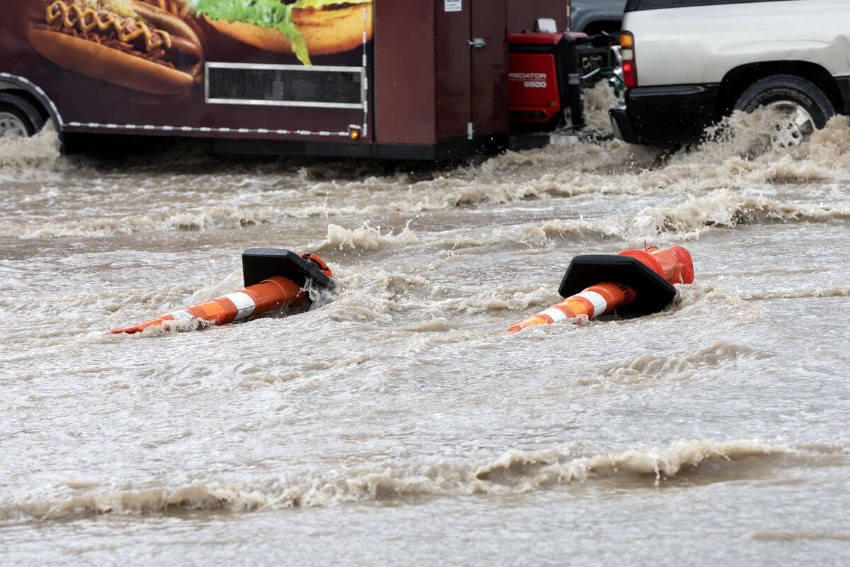 Conos derribados mientras un remolque circula a través de inundaciones repentinas en East Saha ...