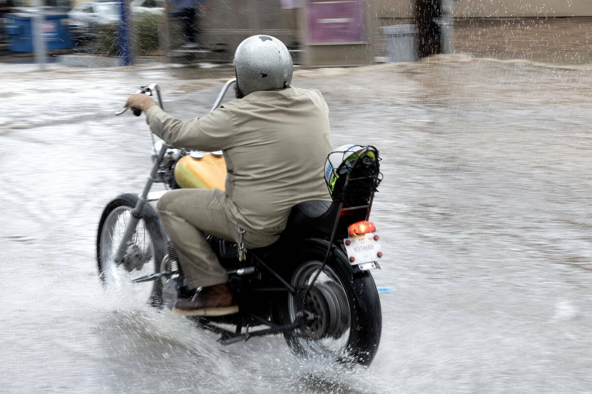 Un motociclista se abre paso a través de las aguas de la inundación en East Sahara Avenue en ...