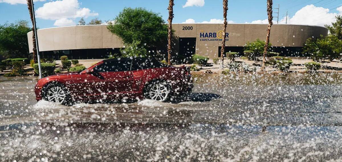 Un auto conduce a través de la inundación residual de las recientes lluvias en North Mojave R ...