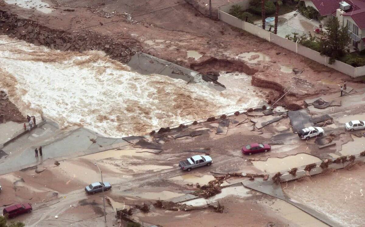 Unos autos se abren paso por el pavimento roto del puente de Spencer Street sobre Flamingo Wash ...