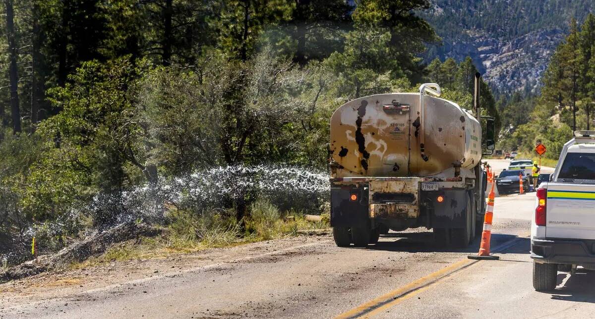 Se rocía agua sobre la tierra compactada para una nueva calzada a lo largo de Kyle Canyon Road ...