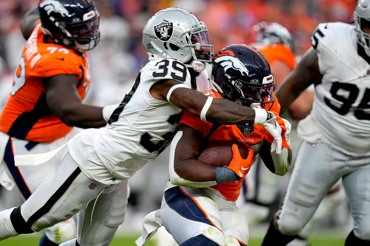 El cornerback de los Raiders de Las Vegas, Nate Hobbs (39), taclea al running back de los Denve ...