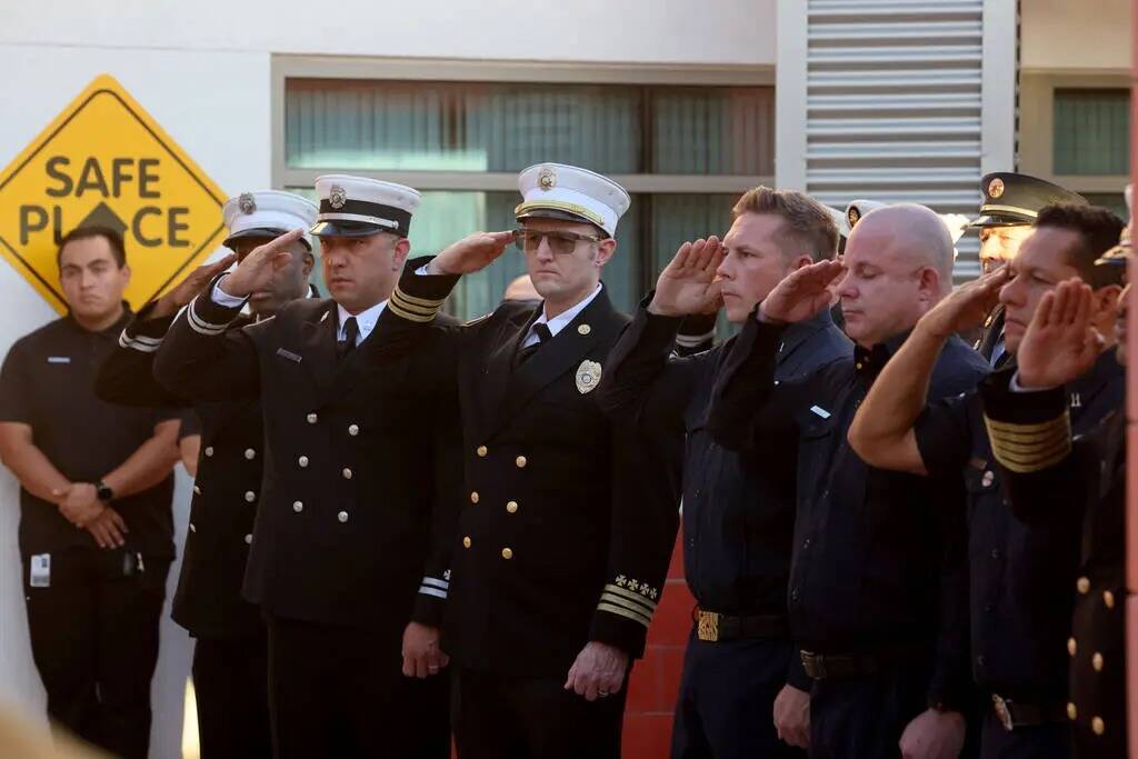 Bomberos de Las Vegas saludan mientras una bandera estadounidense que ondeó sobre el World Tra ...