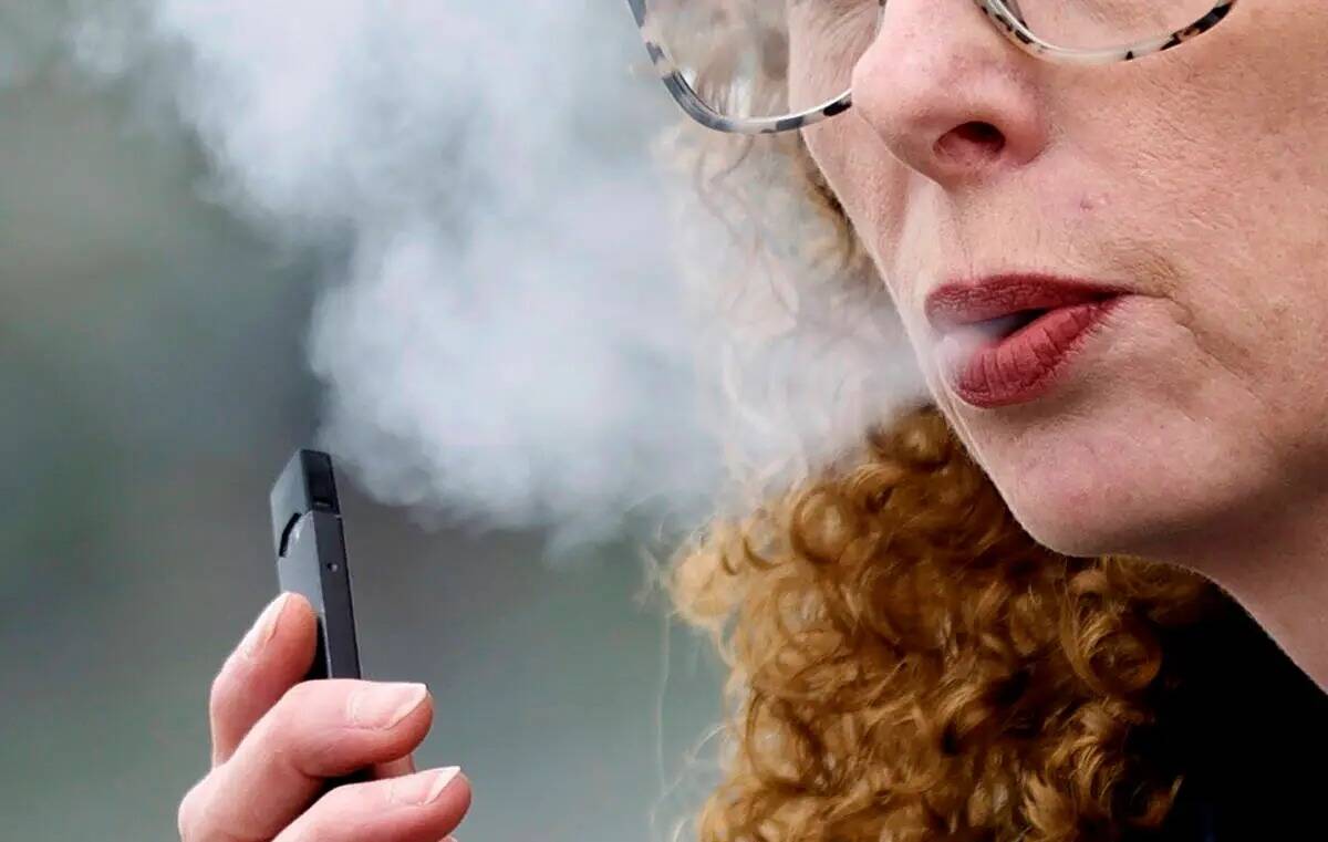 Una mujer exhala mientras vapea de un cigarrillo electrónico Juul pen en Vancouver, Washington ...