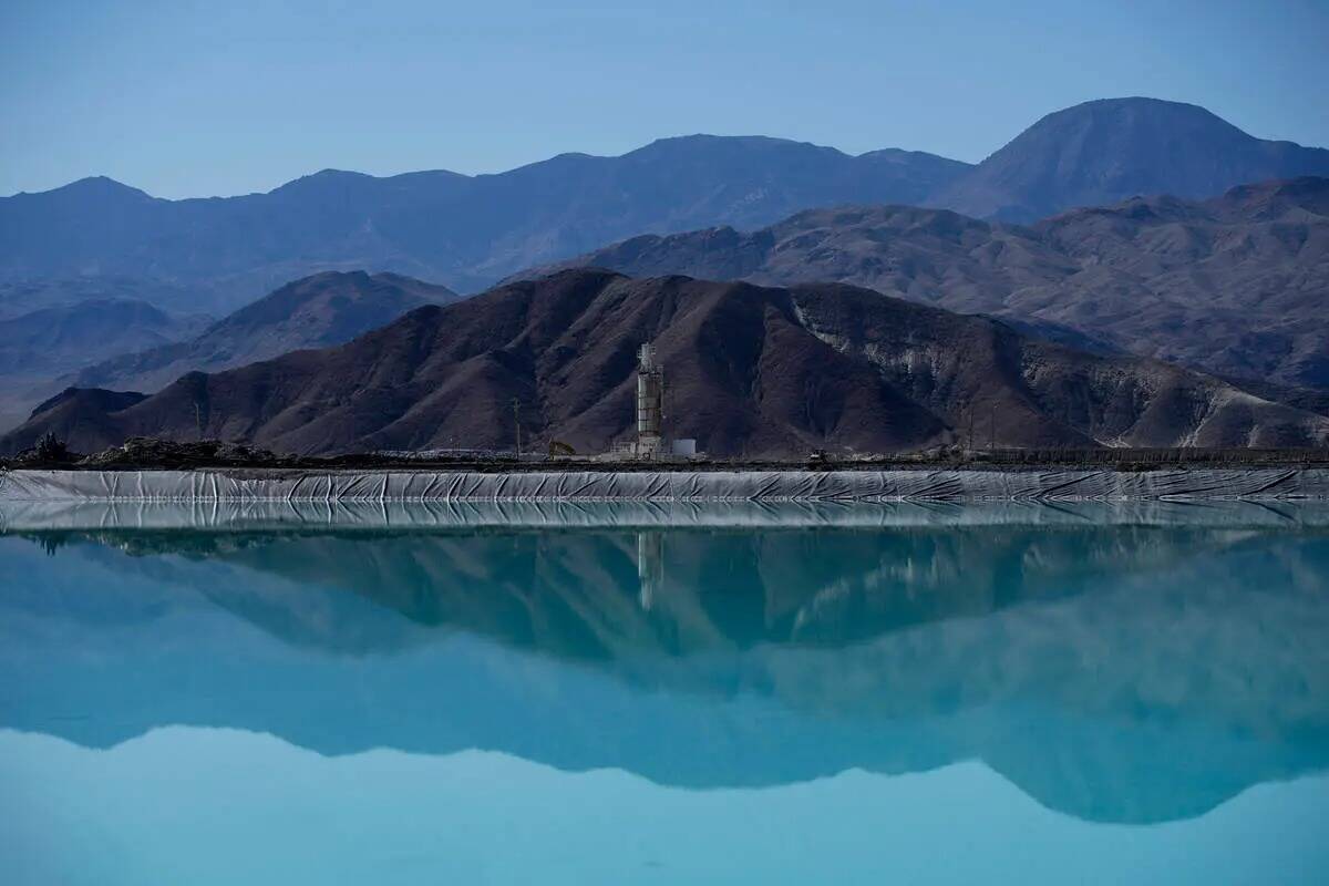 Montañas y una instalación de encalado se reflejan en un estanque de evaporación de salmuera ...