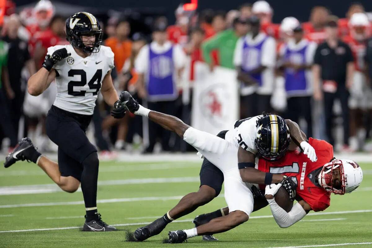 El wide receiver de UNLV Ricky White (11) es tacleado por el safety de Vanderbilt Jalen Gilbert ...