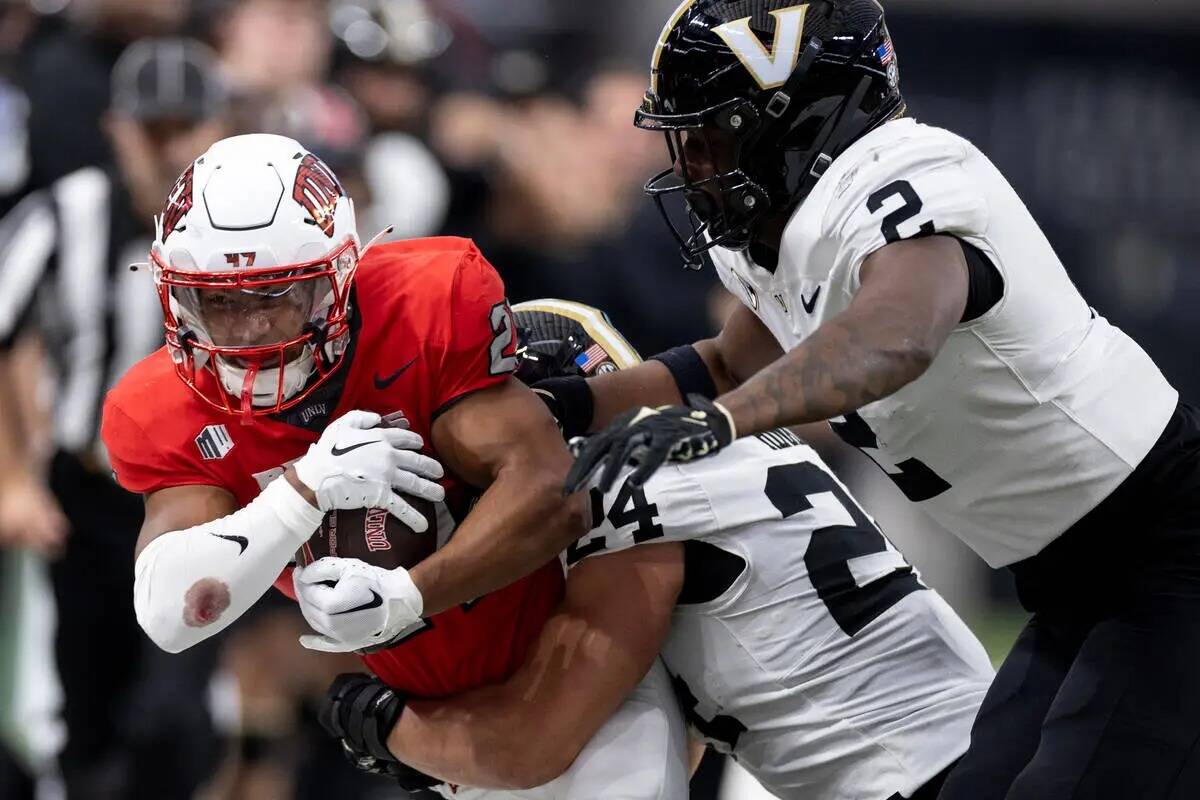 El wide receiver de UNLV Jacob De Jesus (21) es empujado hacia la banda después de hacer una a ...